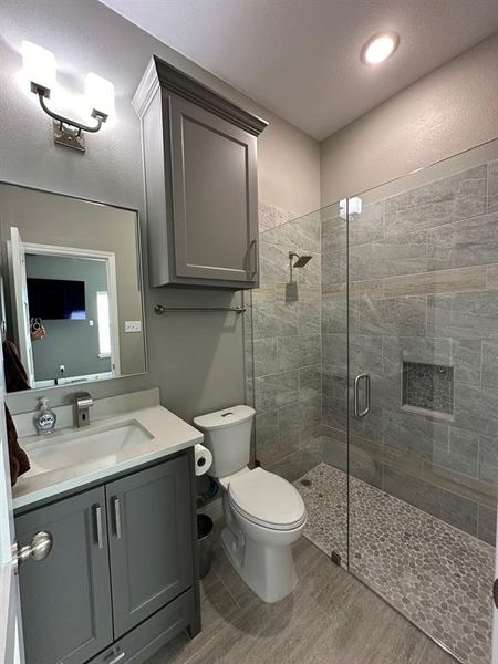 Bathroom featuring an enclosed shower, vanity, toilet, and a textured ceiling