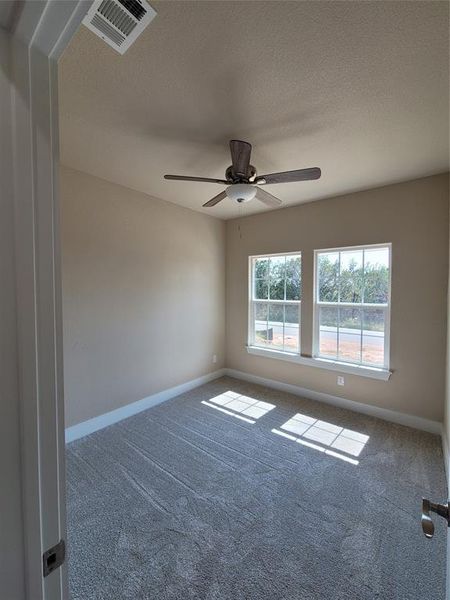 Unfurnished room featuring a textured ceiling, ceiling fan, and carpet