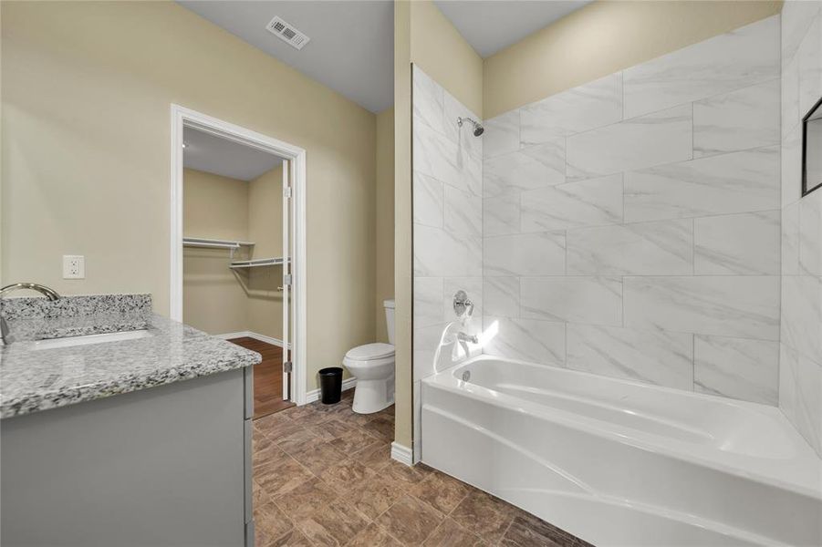 Full bathroom featuring tile patterned flooring, tiled shower / bath combo, toilet, and vanity