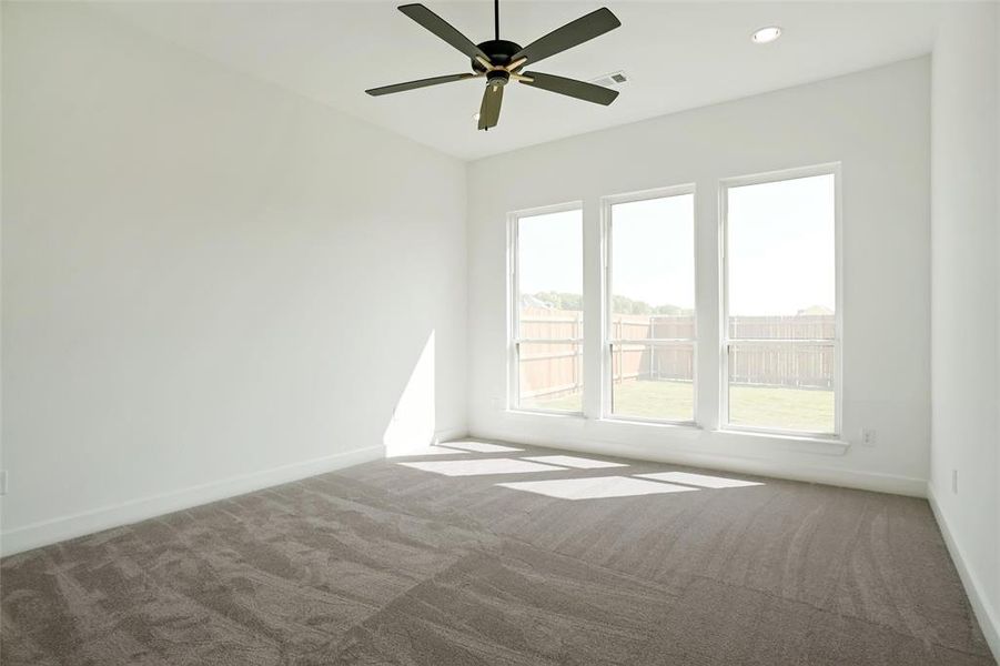 Carpeted spare room featuring ceiling fan