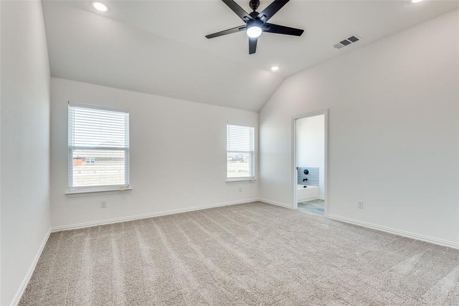 Carpeted empty room with ceiling fan and lofted ceiling