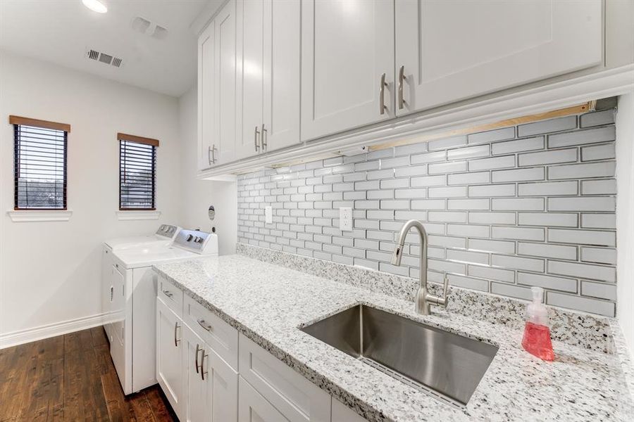 This is a well-lit laundry room featuring stainless steel sink and sunny windows.