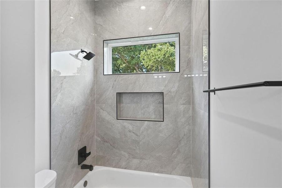 Bathroom with tiled shower / bath combo and toilet