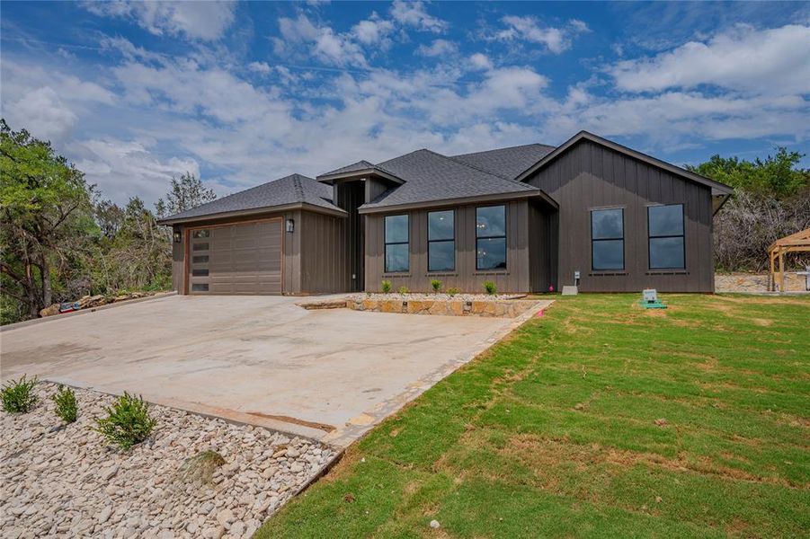 View of front of property featuring a garage and a front lawn