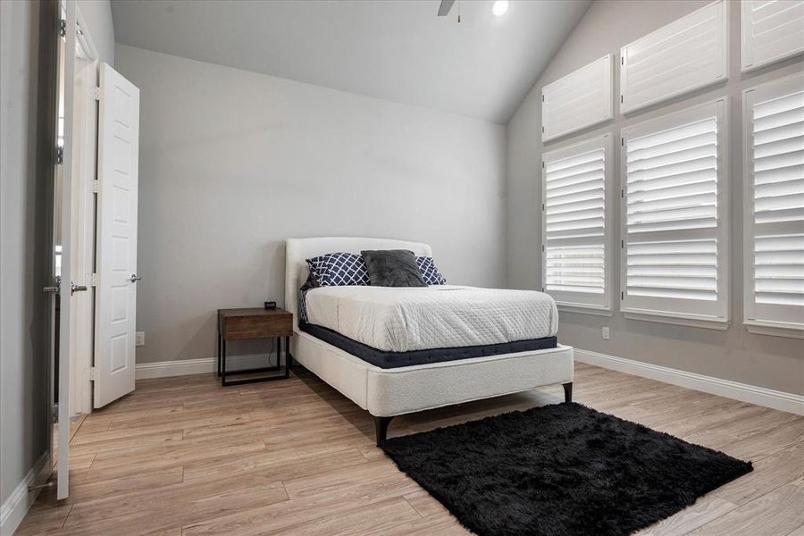 Bedroom with vaulted ceiling, light hardwood / wood-style flooring, and ceiling fan