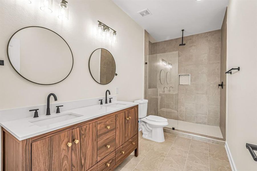 Double sinks in the primary bath with designer wood vanity. Seamless glass shower panel and attractive tile flooring and inset.