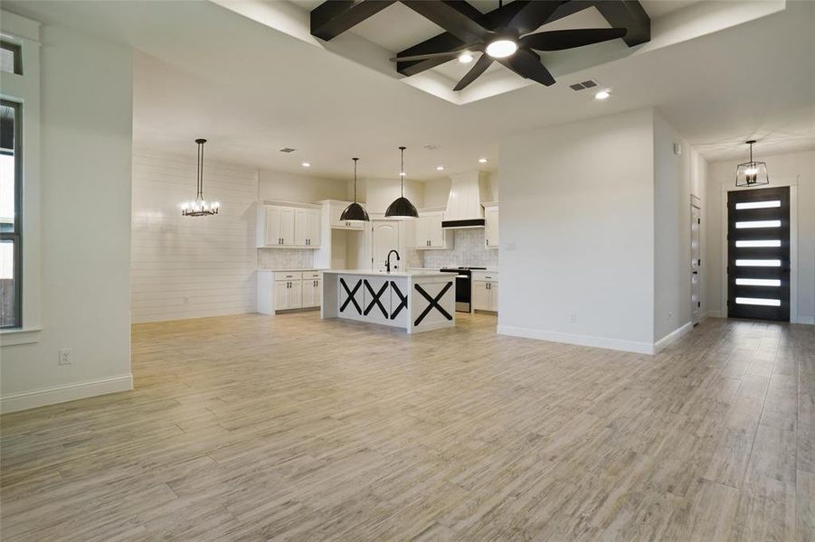 Living room featuring beamed ceiling, ceiling fan with notable chandelier, light wood-type flooring, and sink