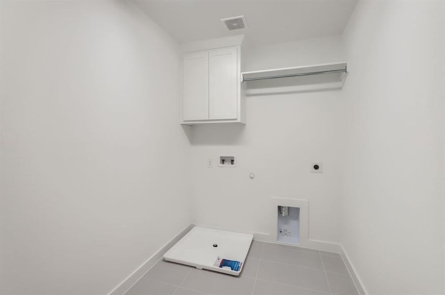 Clothes washing area featuring cabinets, light tile patterned floors, hookup for a washing machine, electric dryer hookup, and hookup for a gas dryer