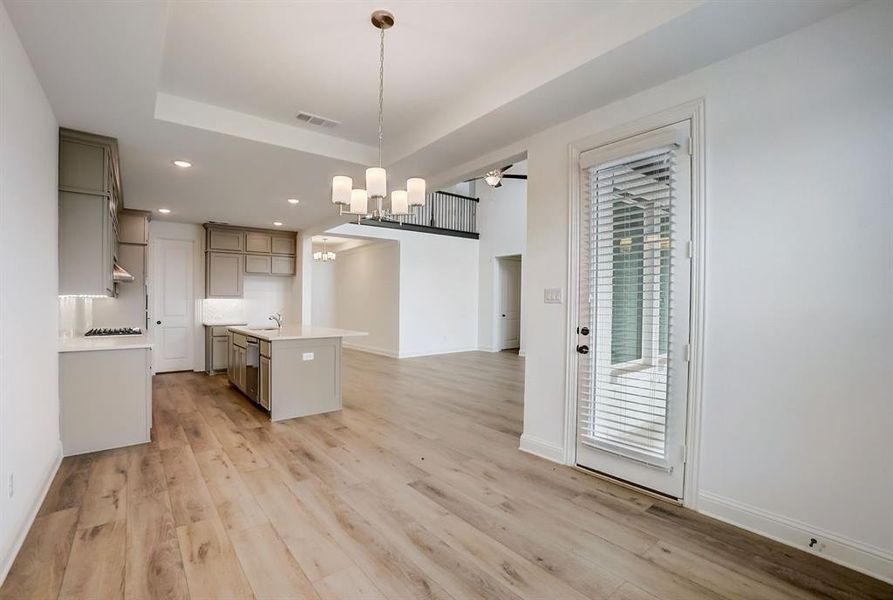 Kitchen with a center island, light hardwood / wood-style flooring, and a raised ceiling