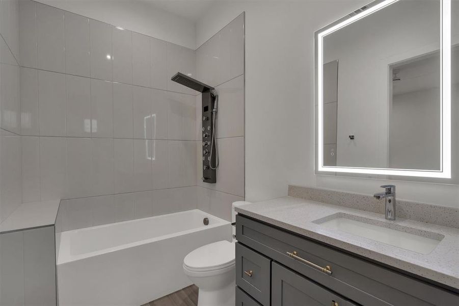 Full bathroom with tiled shower / bath, vanity, toilet, and hardwood / wood-style flooring