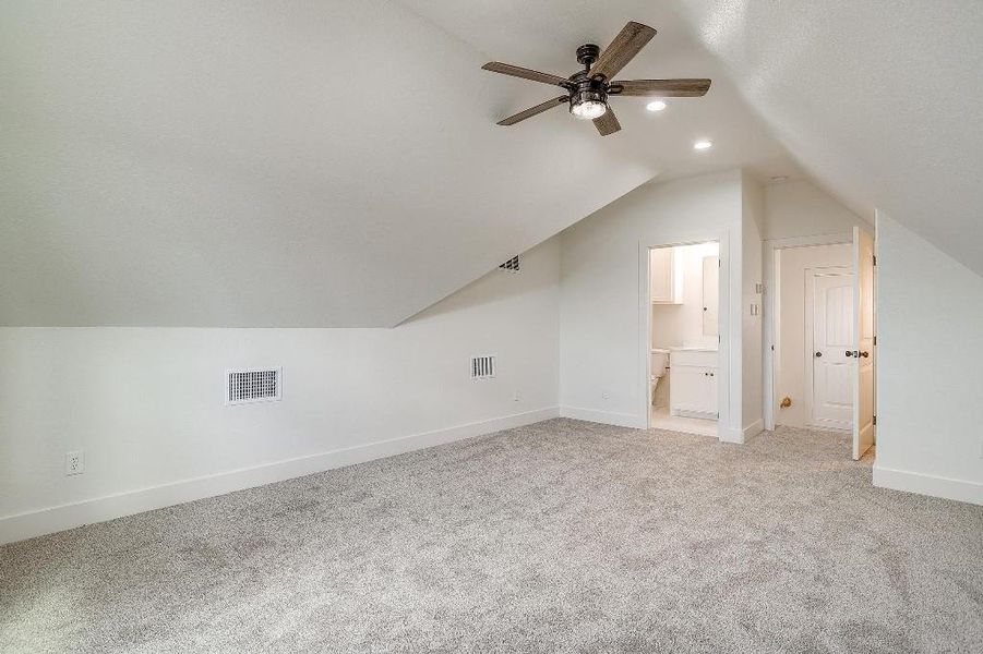 Bonus room with vaulted ceiling, light colored carpet, and ceiling fan