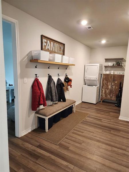 Mudroom featuring wood-type flooring and stacked washer and clothes dryer