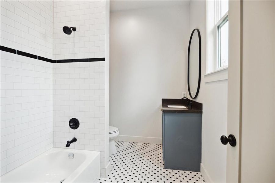 This full bath is accessible to the upstairs guest bedroom and the gameroom. The classic tile selections blend well with with the painted vanity with black quartz counter and matte black hardware.