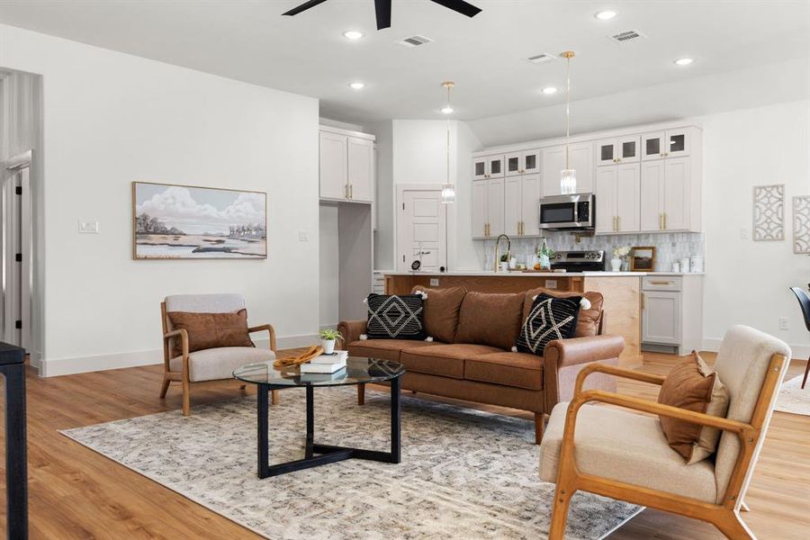 Living room with light wood-type flooring, ceiling fan, and sink