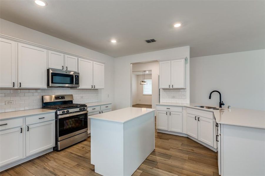 Kitchen featuring light wood-type flooring, white cabinetry, sink, and stainless steel appliances