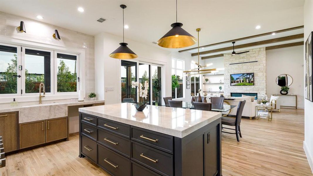 Kitchen with a stone fireplace, light hardwood / wood-style flooring, a wealth of natural light, and a kitchen island