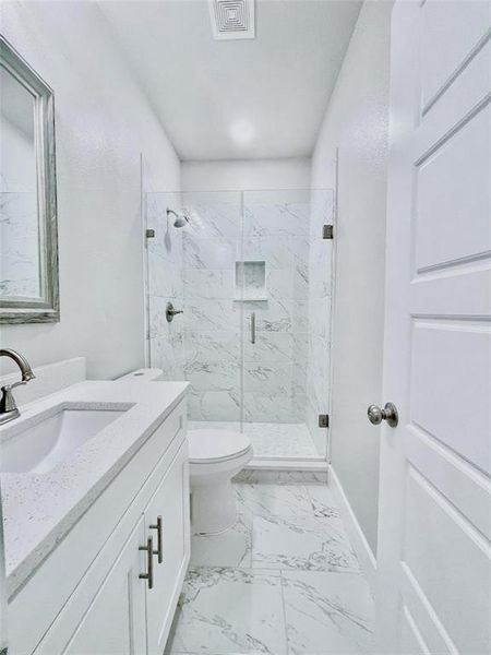 Bathroom featuring walk in shower, vanity, and toilet