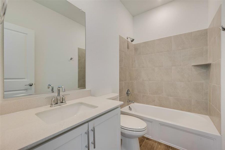 Full bathroom with vanity, tiled shower / bath combo, and toilet