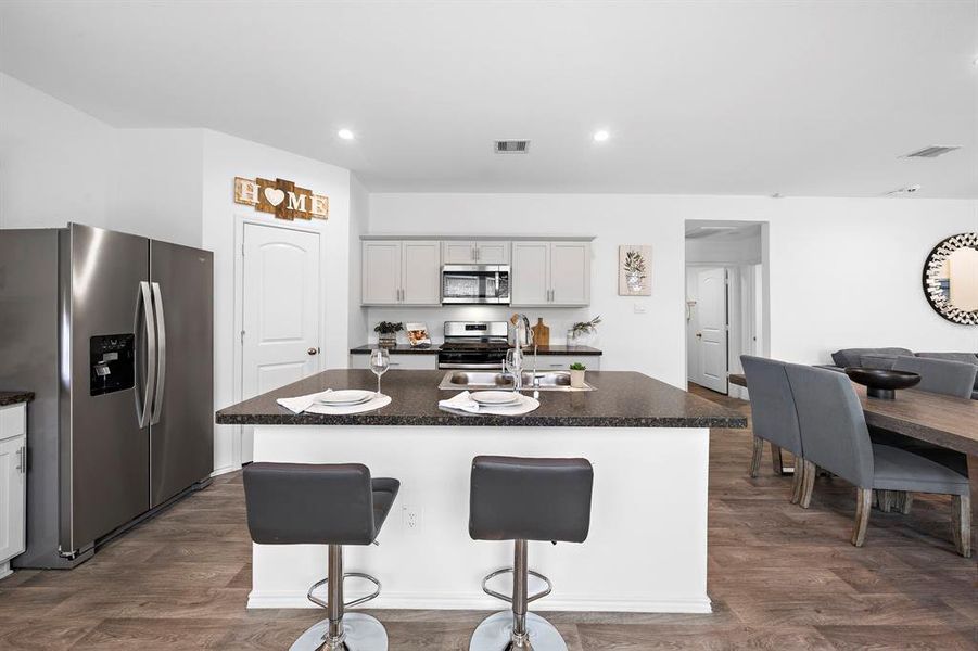 The open-concept kitchen offers a central granite island with bar seating. The space flows seamlessly into the dining area, making it ideal for entertaining.