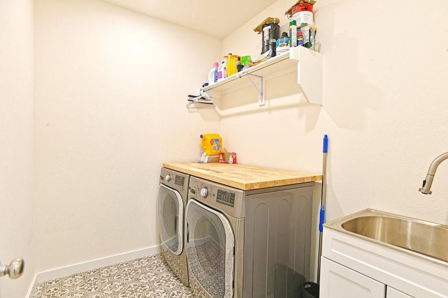 Laundry room featuring sink, washer and clothes dryer, and light tile flooring