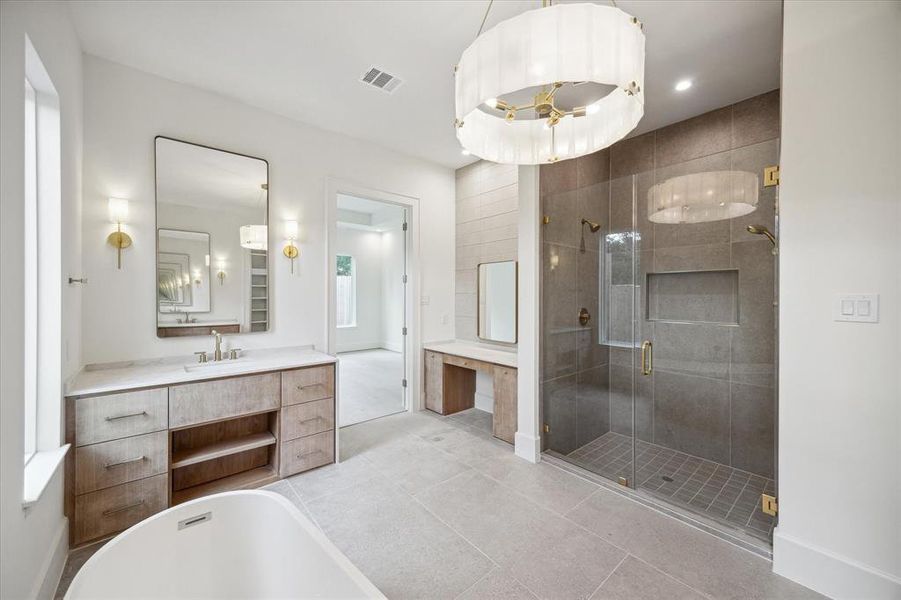 The over-sized shower is complete with full-height tiled walls, brass fixtures and hardware. A nearby dressing table provides a seated spot to get ready for the day.