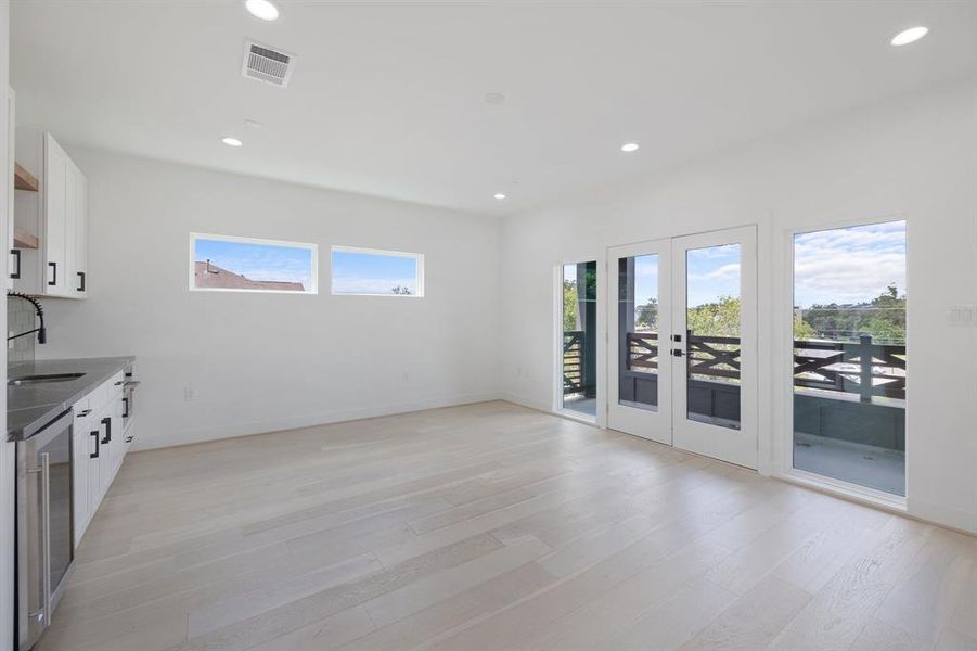 Another view of this large game room.  The beautiful white oak floors and large windows make this space light and bright.  The kitchenette is perfect for movie nights or cookouts on the patio.