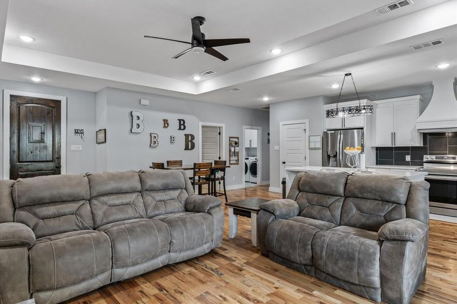 Living room with ceiling fan, light wood-type flooring, and washer / dryer