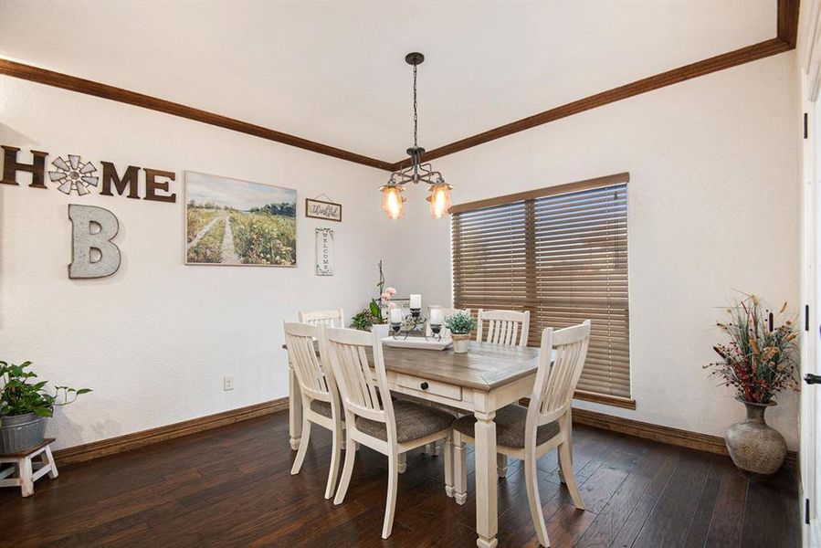 Dining room with ornamental molding, dark wood-type flooring, and a chandelier