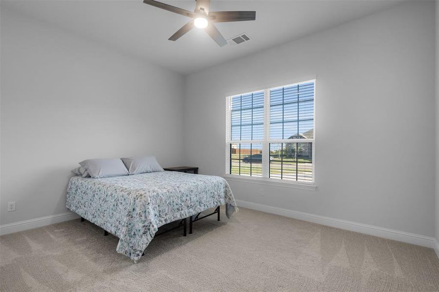 Guest Bedroom 1 with ceiling fan and light carpet