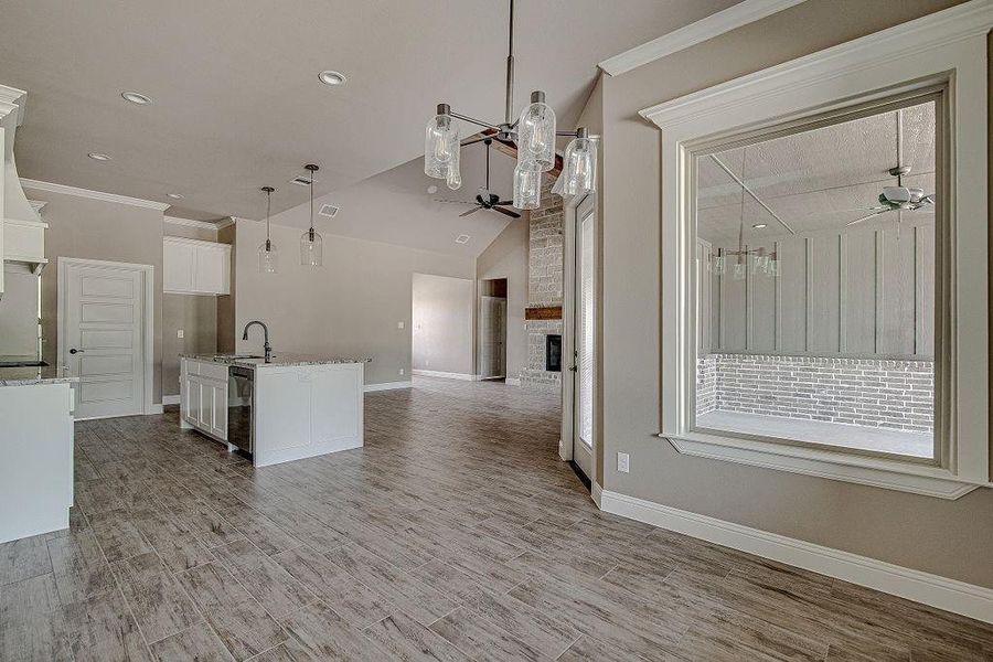 Kitchen featuring white cabinets, an island with sink, brick wall, and ceiling fan