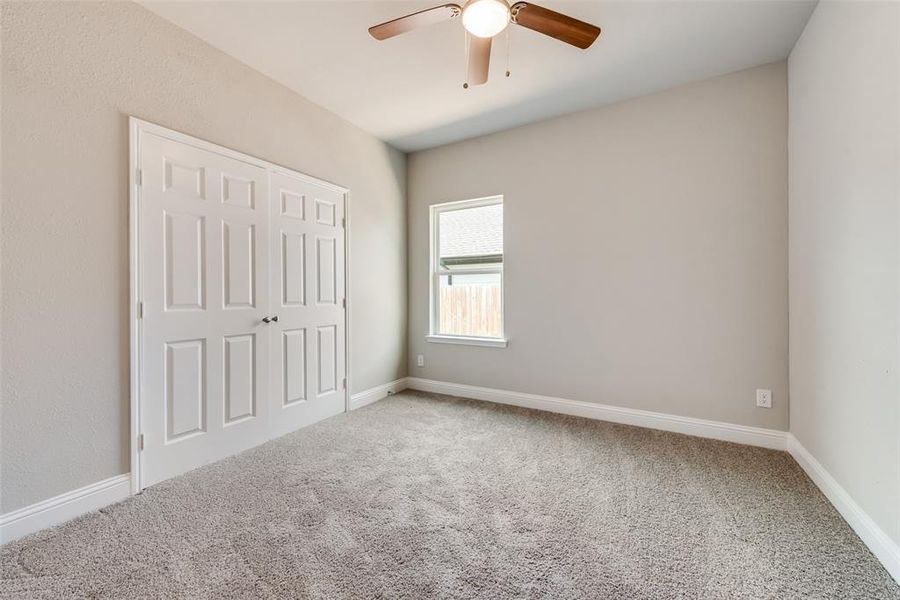 Unfurnished bedroom featuring carpet, ceiling fan, and a closet