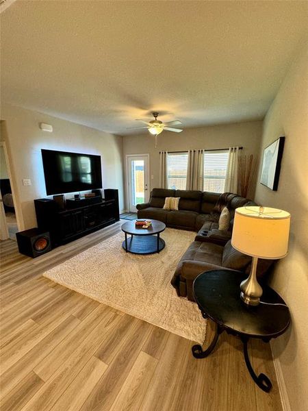 Living room featuring a textured ceiling, hardwood / wood-style flooring, and ceiling fan