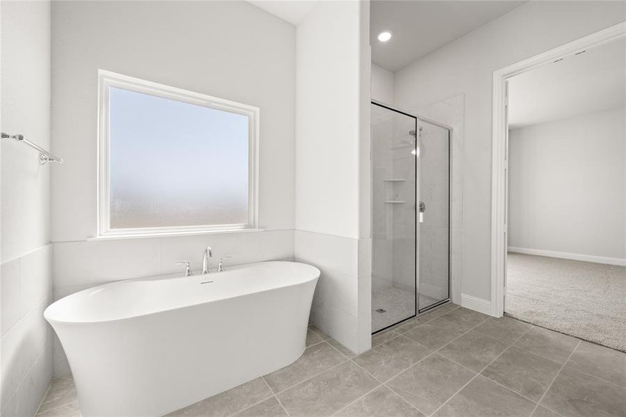 Bathroom with shower with separate bathtub and tile patterned floors