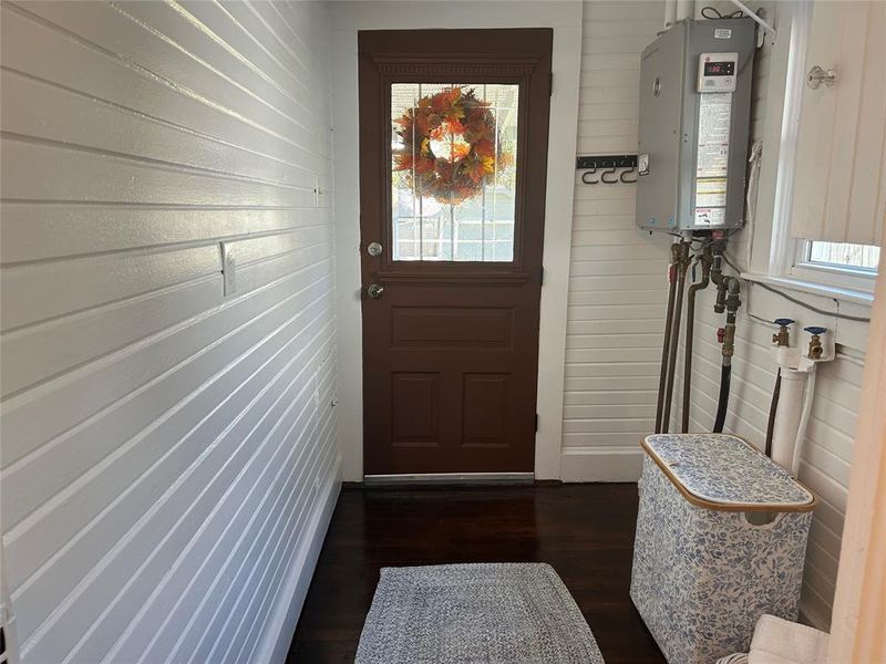 Backdoor, in Laundry Room, featuring dark hardwood / wood-style flooring and wooden walls