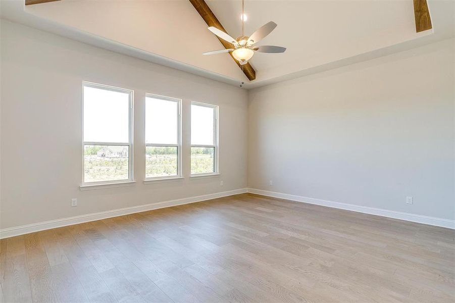 Spare room featuring light hardwood / wood-style floors, beam ceiling, and ceiling fan