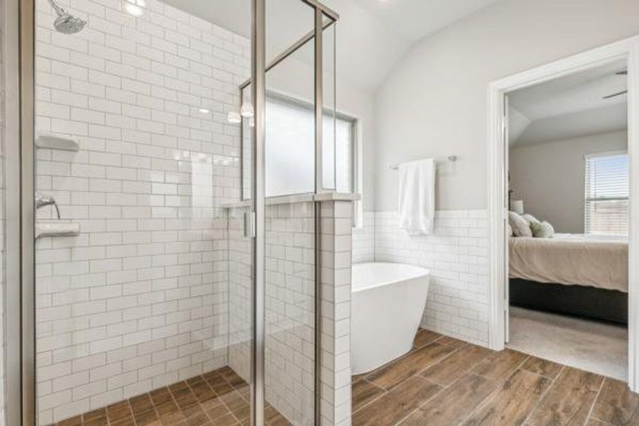 Bathroom with hardwood / wood-style flooring, separate shower and tub, vaulted ceiling, and tile walls