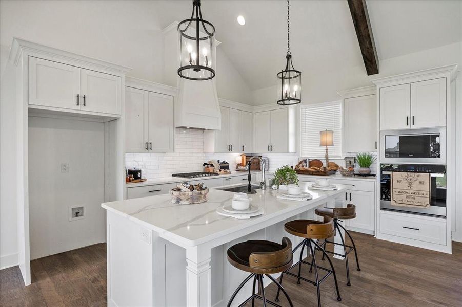 Kitchen featuring appliances with stainless steel finishes, vaulted ceiling with beams, dark hardwood / wood-style floors, and white cabinetry