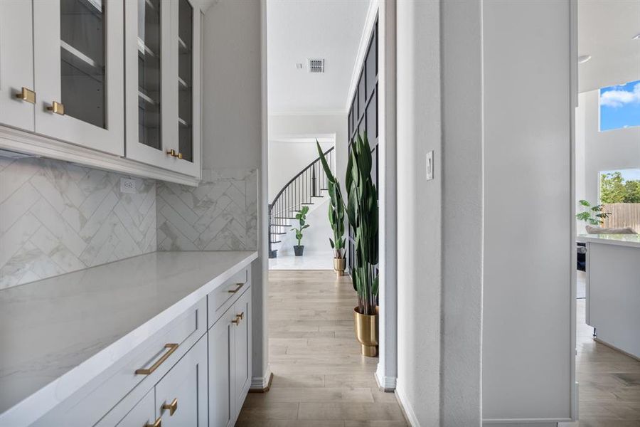 Luxury and functionality, from the dining room to the kitchen is a butlers pantry featuring more storage with uppers and lowers, light counters, upgraded backsplash and countertops as well as upgraded upper doors with glass and upgraded hardware accenting this luxury home.