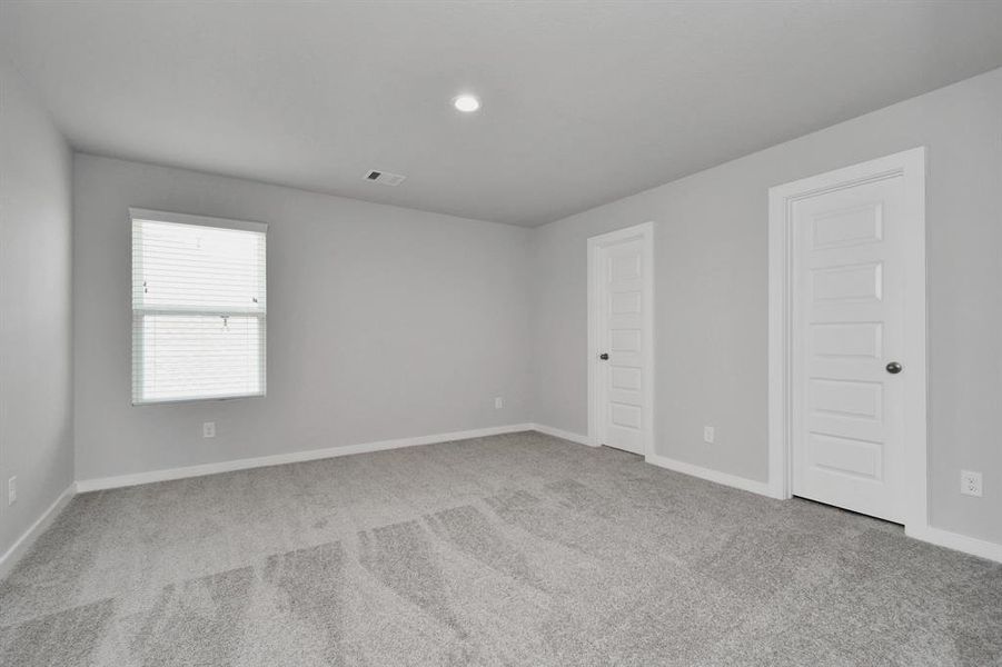 Secondary bedroom. Plush carpet, neutral paint color, large windows, and spacious closets.