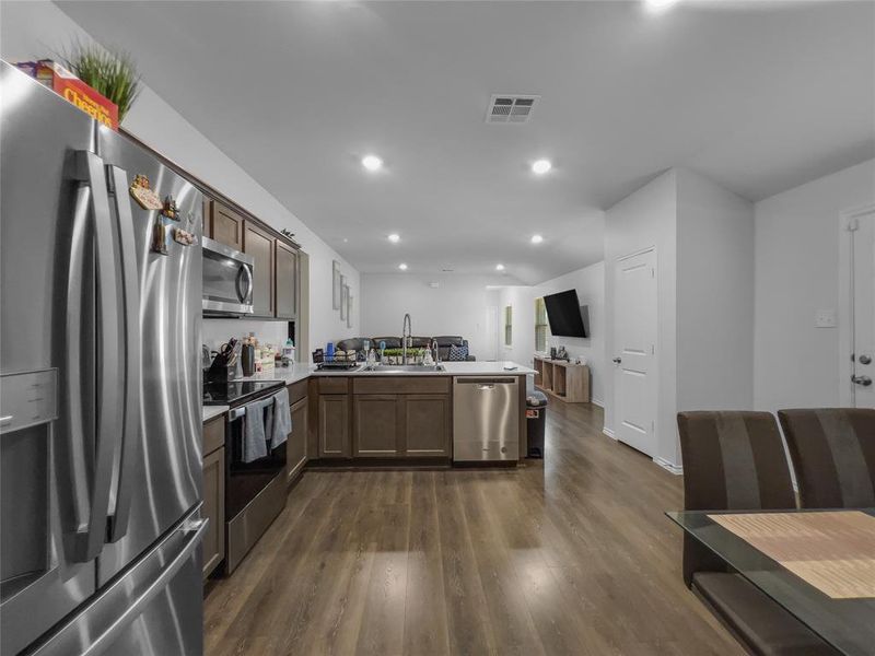 Kitchen featuring kitchen peninsula, appliances with stainless steel finishes, dark wood-type flooring, and sink