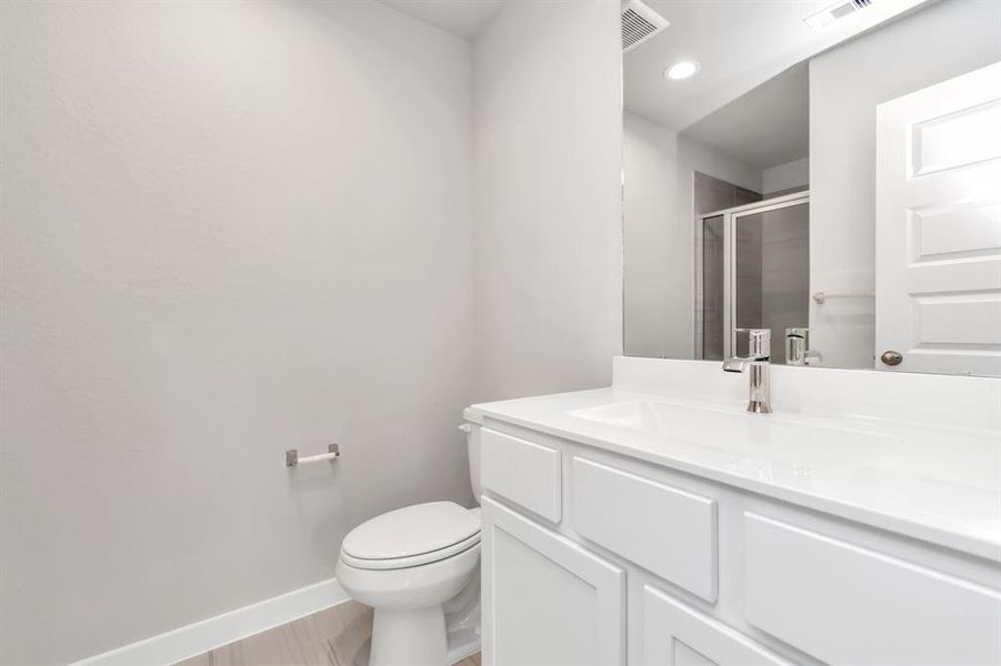 Experience sophistication in the guest suite bathroom, where tile flooring complements a walk-in shower with tile surround. Light wood cabinets complete with a beautiful light countertop, enhances the space for a truly inviting ambiance. Sample photo of completed home with similar floor plan. As-built interior colors and selections may vary.