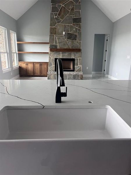 Kitchen featuring lofted ceiling, sink, and a fireplace