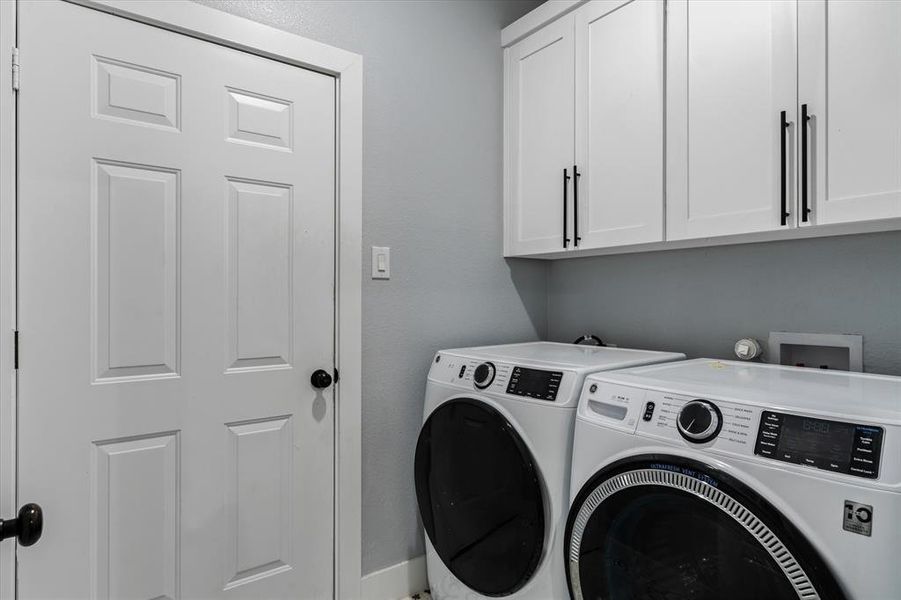 Clothes washing area featuring washer and clothes dryer and cabinets