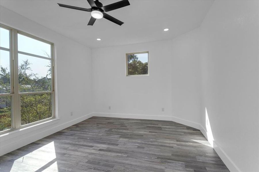 Unfurnished room featuring dark hardwood / wood-style flooring, a wealth of natural light, and ceiling fan