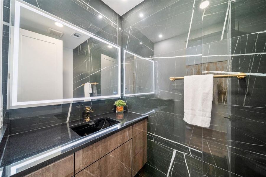 Bathroom featuring backsplash, vanity, and tile walls