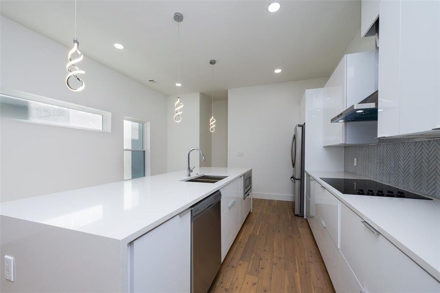 Kitchen featuring decorative light fixtures, tasteful backsplash, white cabinets, sink, and appliances with stainless steel finishes