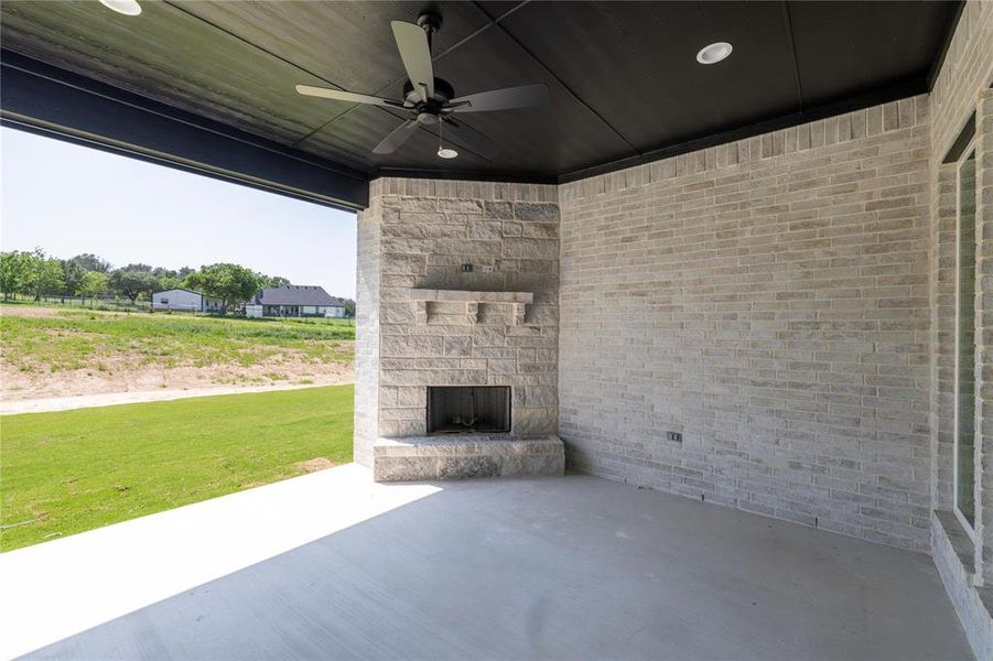 View of patio / terrace featuring an outdoor stone fireplace and ceiling fan