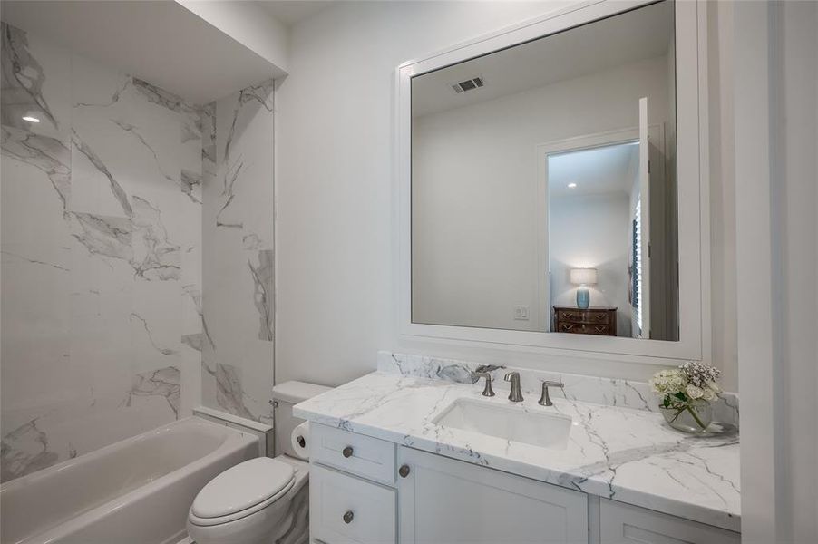 En-suite bath features marble counters and marble surround in shower/bath.