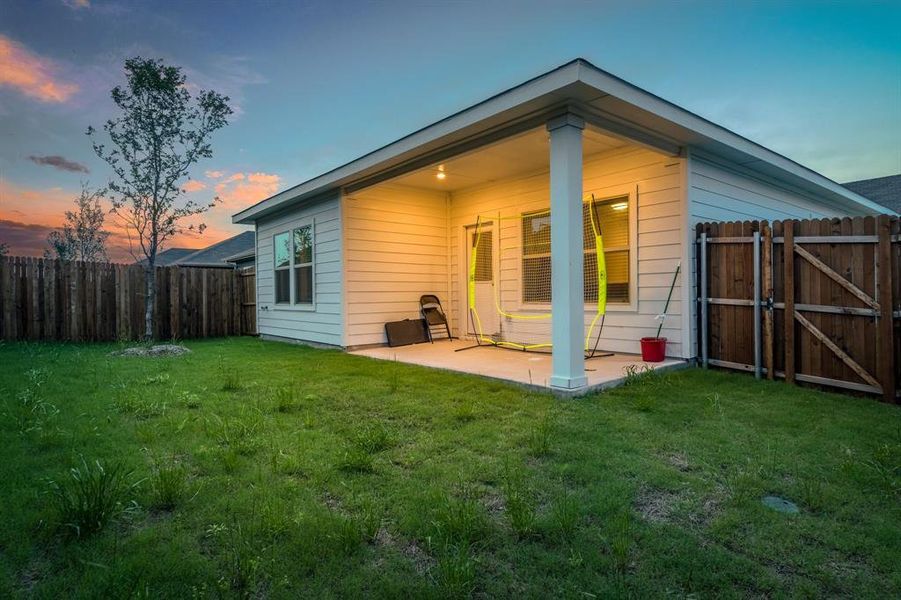 Back house at dusk with a yard and a patio area