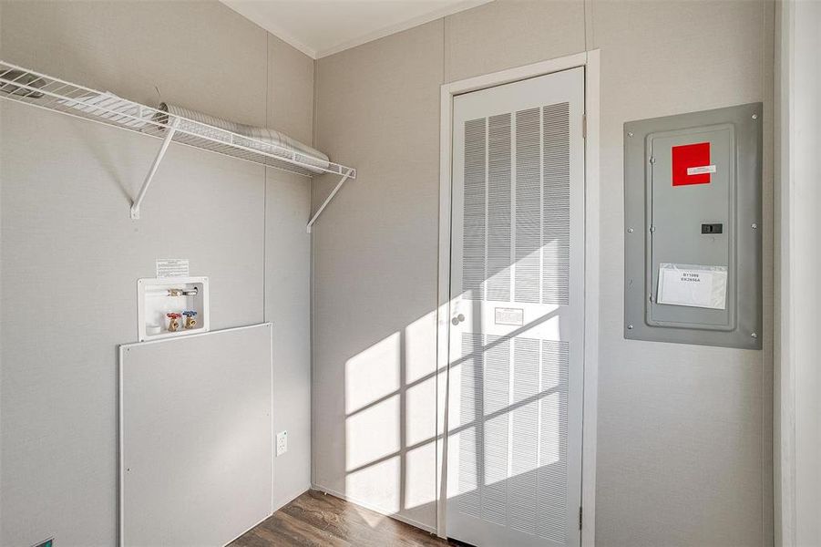 Clothes washing area with ornamental molding, electric panel, dark hardwood / wood-style floors, and washer hookup